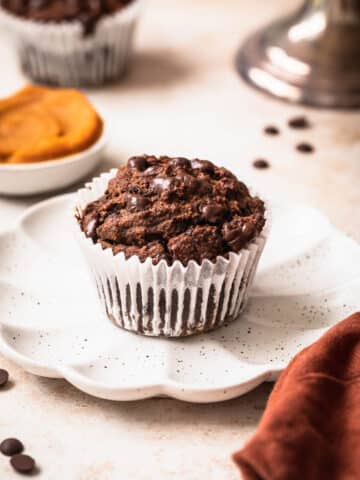 Chocolate sweet potato muffin on a small plate with pureed sweet potato in the background.