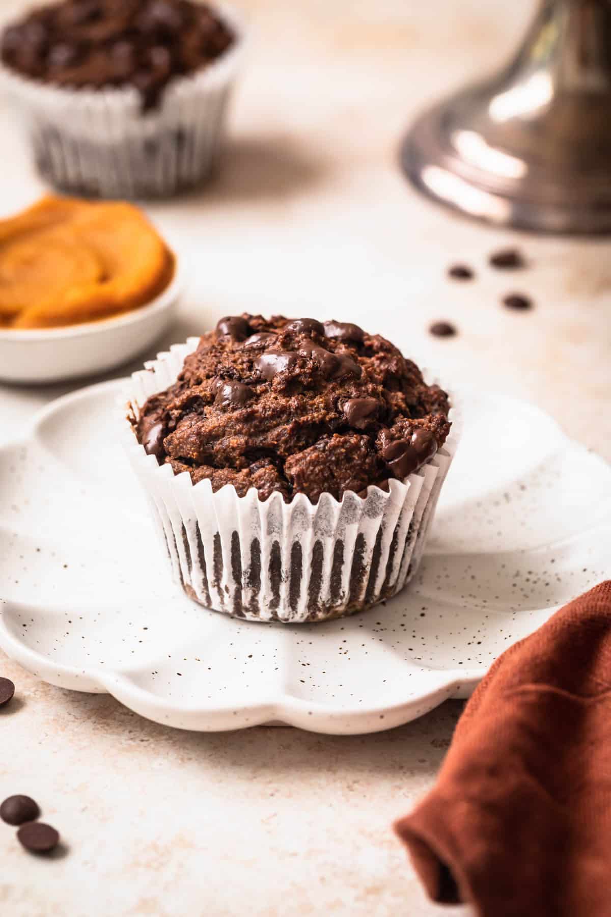 Chocolate sweet potato muffin on a small plate with pureed sweet potato in the background.