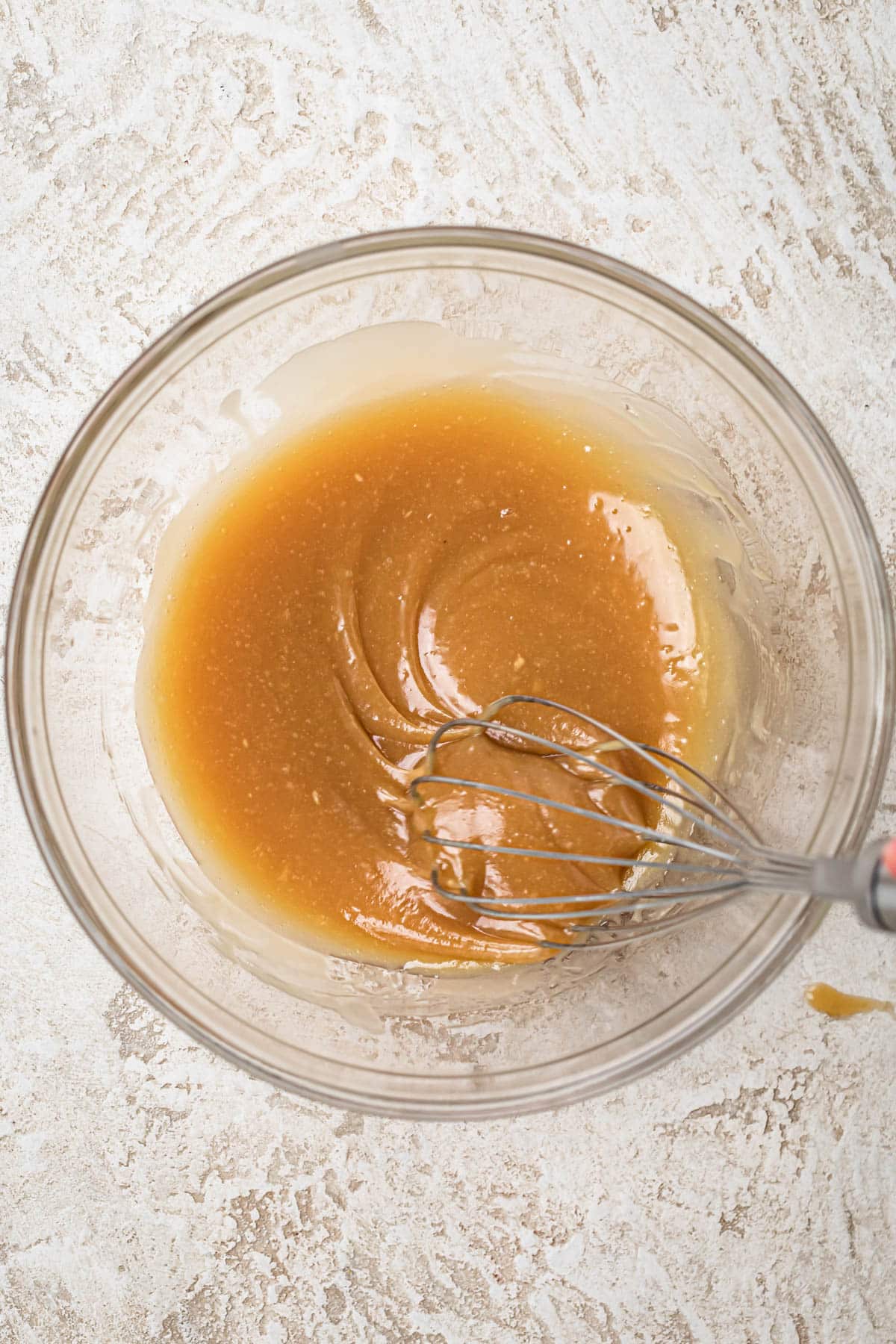 Tahini, maple syrup, macadamia oil and vanilla extract whisked together in a medium glass mixing bowl.