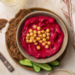 Roasted beetroot hummus in a bowl topped with chickpeas.