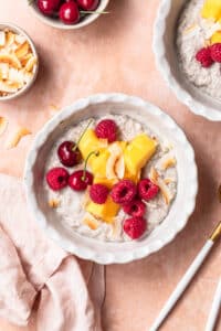Coconut chia pudding in a bowl topped with fresh mango and berries.