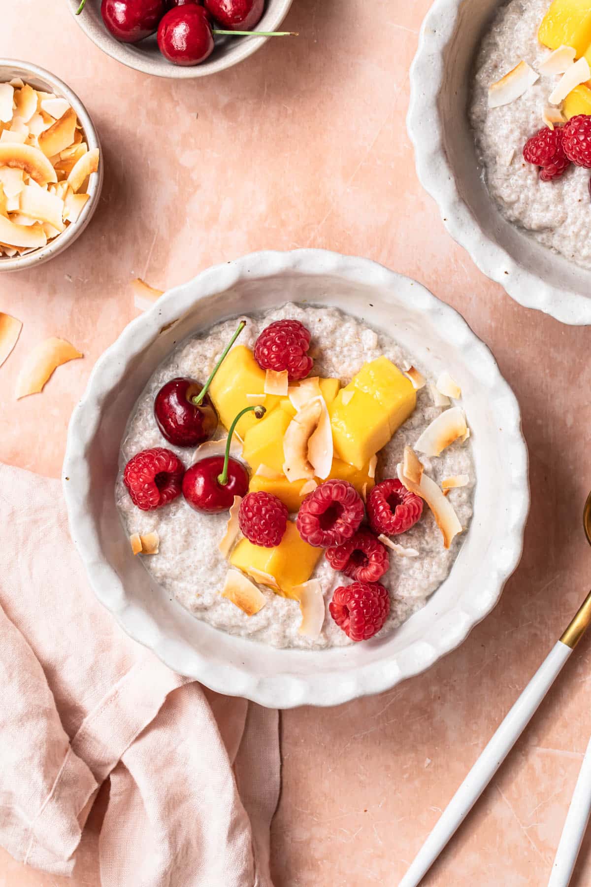 Coconut chia pudding in a bowl topped with fresh mango and berries.