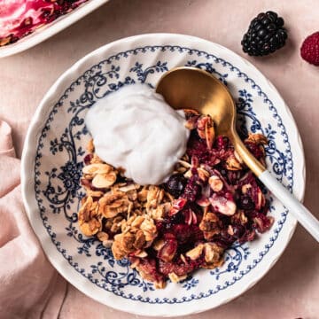 Berry breakfast crumble in a vintage blue and white bowl, topped with a dollop of yoghurt.