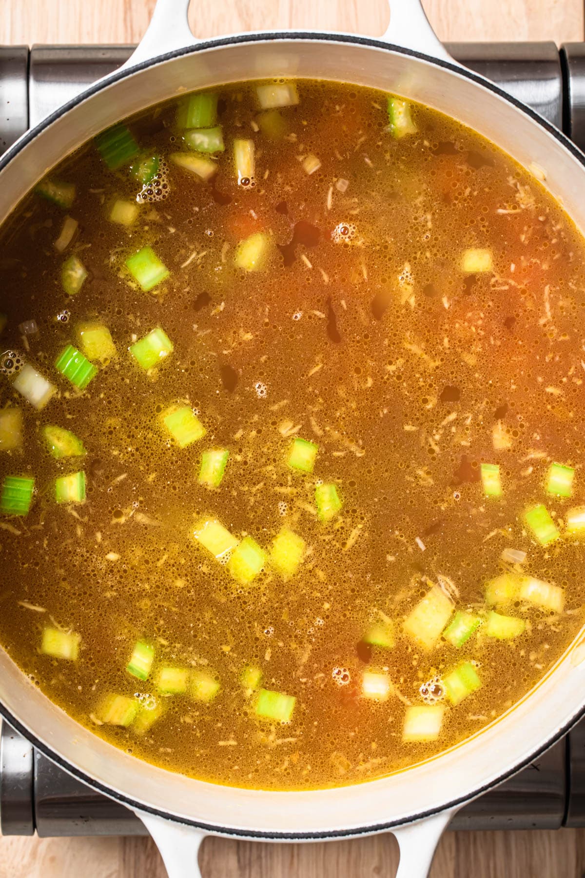 Broth added to a large pot with vegetables.