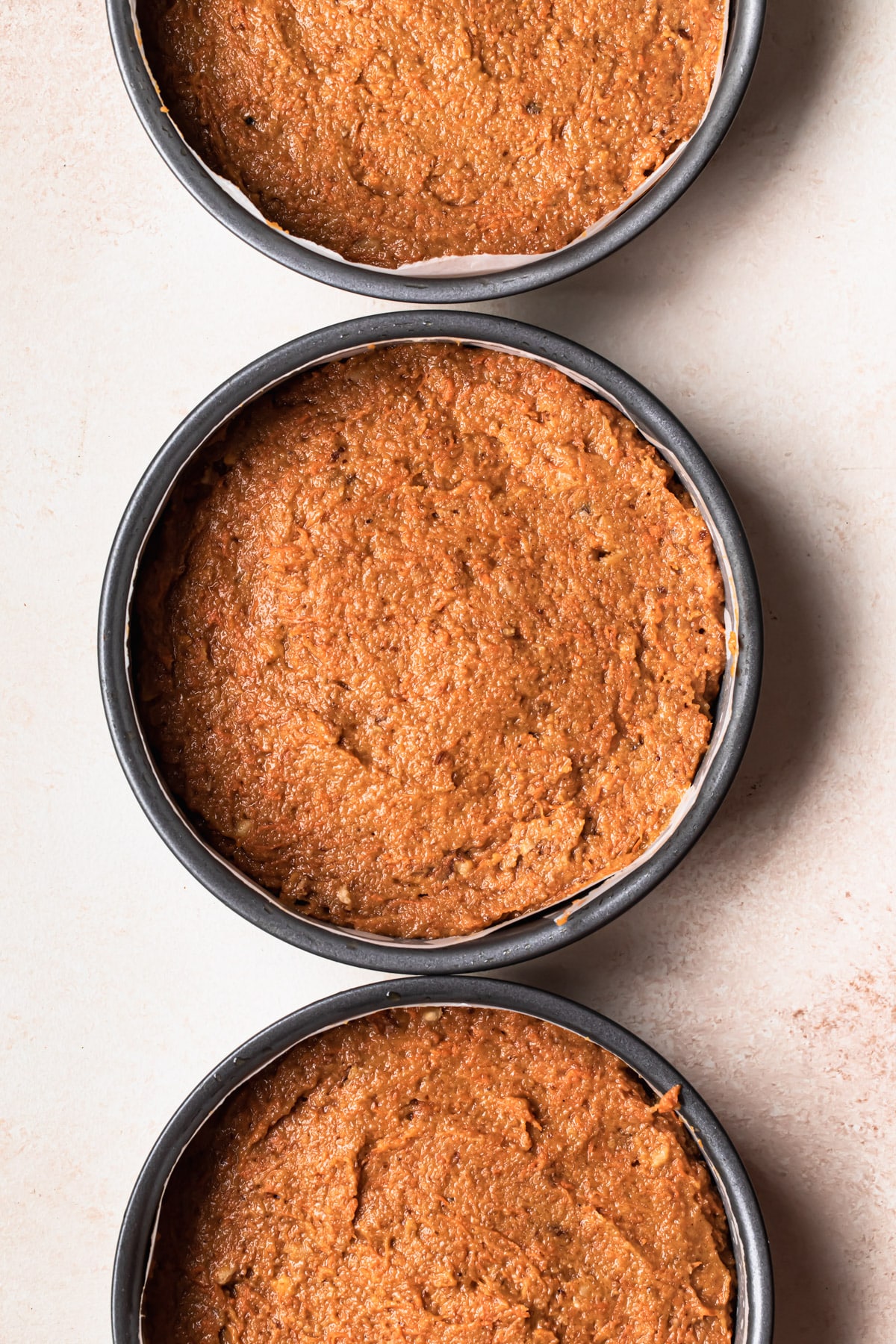 Healthy Carrot Cake mixture divided between 3 baking paper lined 7 Inch cake tins.