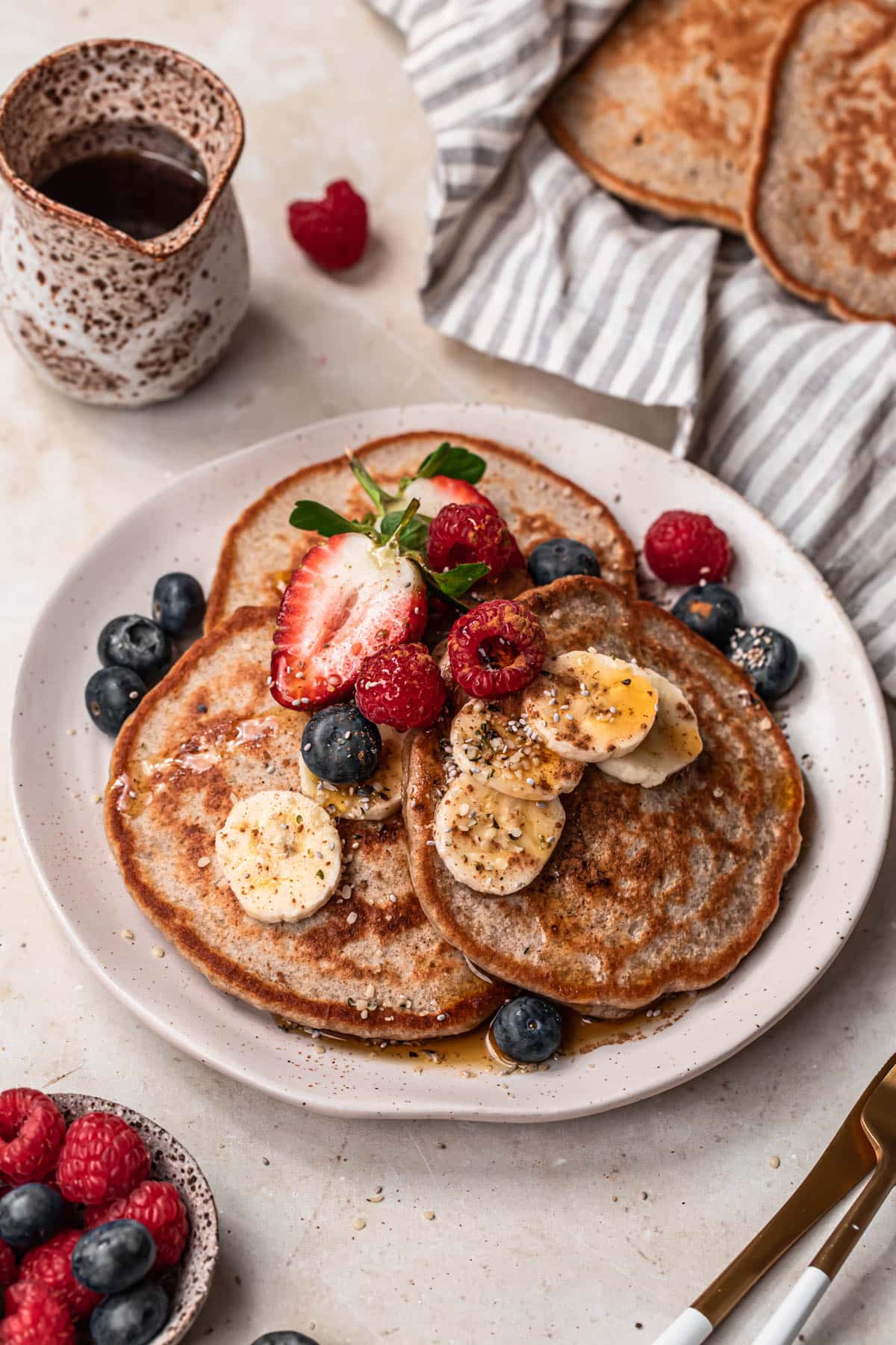 A plate of banana buckwheat pancakes topped with fresh banana slices and berries.