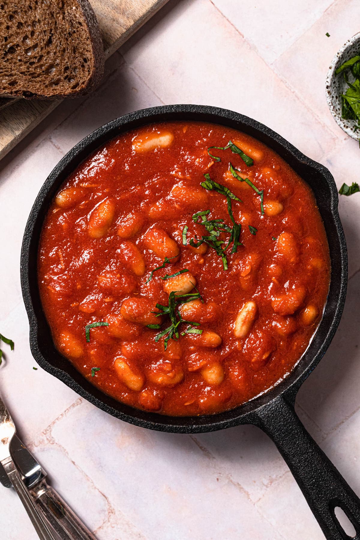 Healthy baked beans in a small frypan with toast and topped with herbs