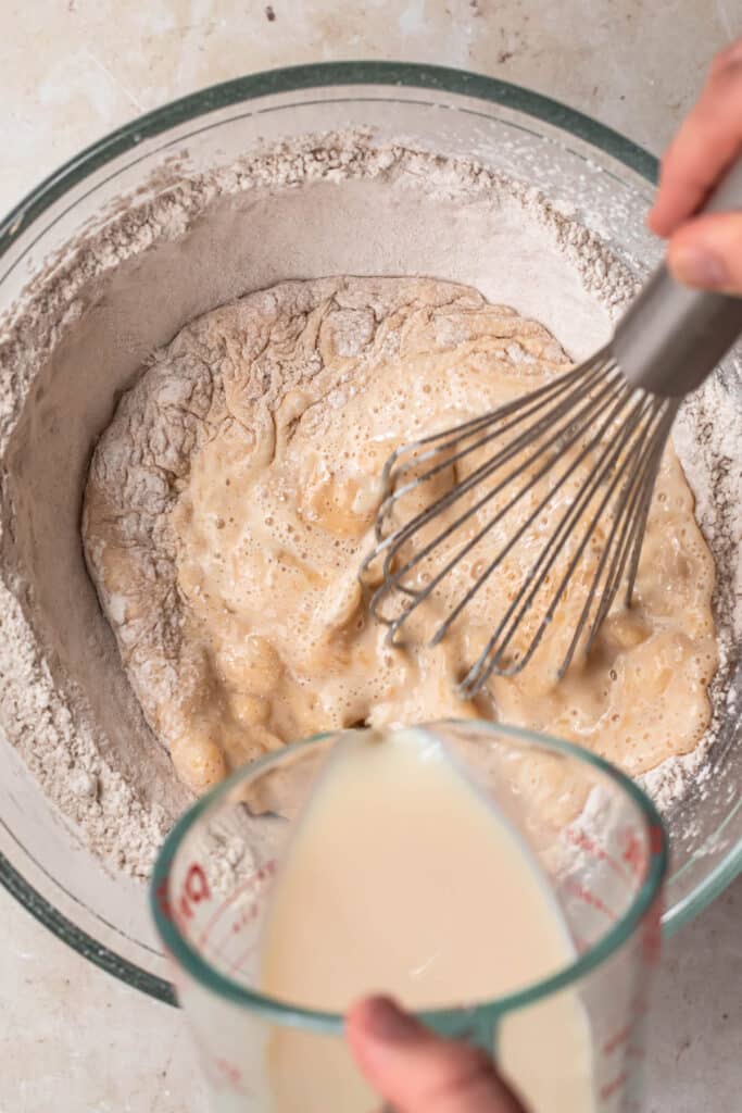 Milk being poured into a mixing bowl with buckwheat flour.