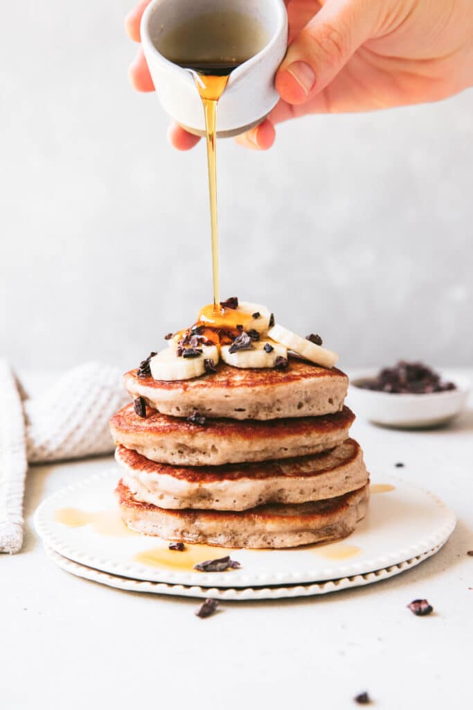 gluten free banana buckwheat pancake stack topped with banana slices and maple syrup poured over the top