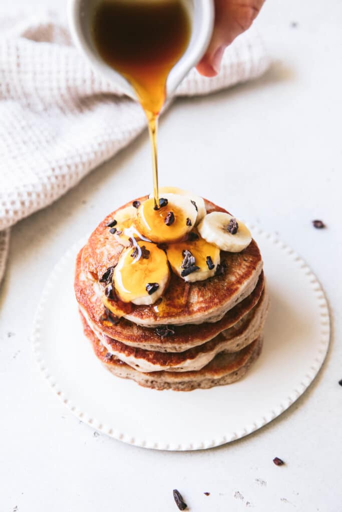 maple syrup poured over top of buckwheat pancake stack