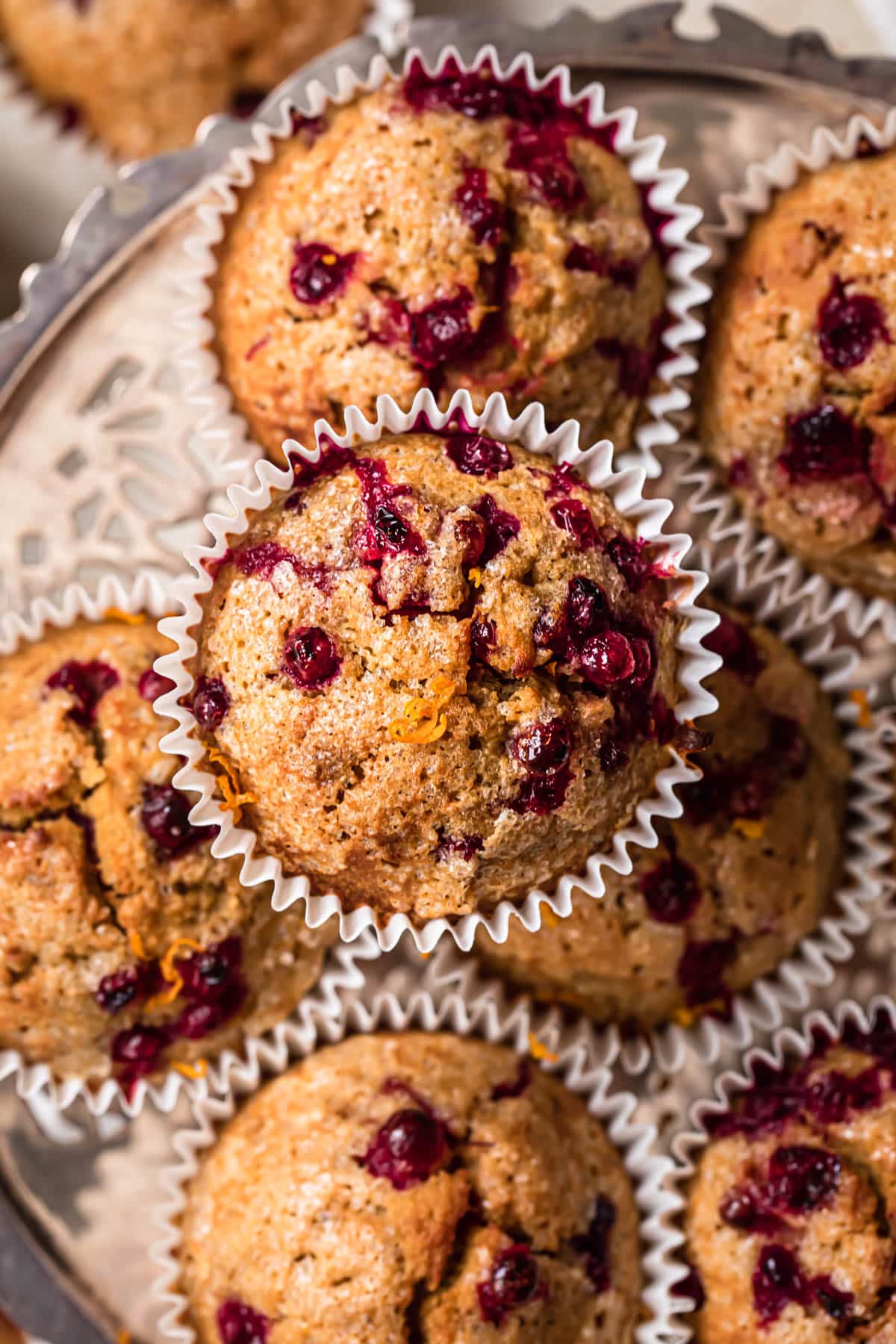 Top down, close up photo of gluten free orange cranberry muffins on a silver platter.