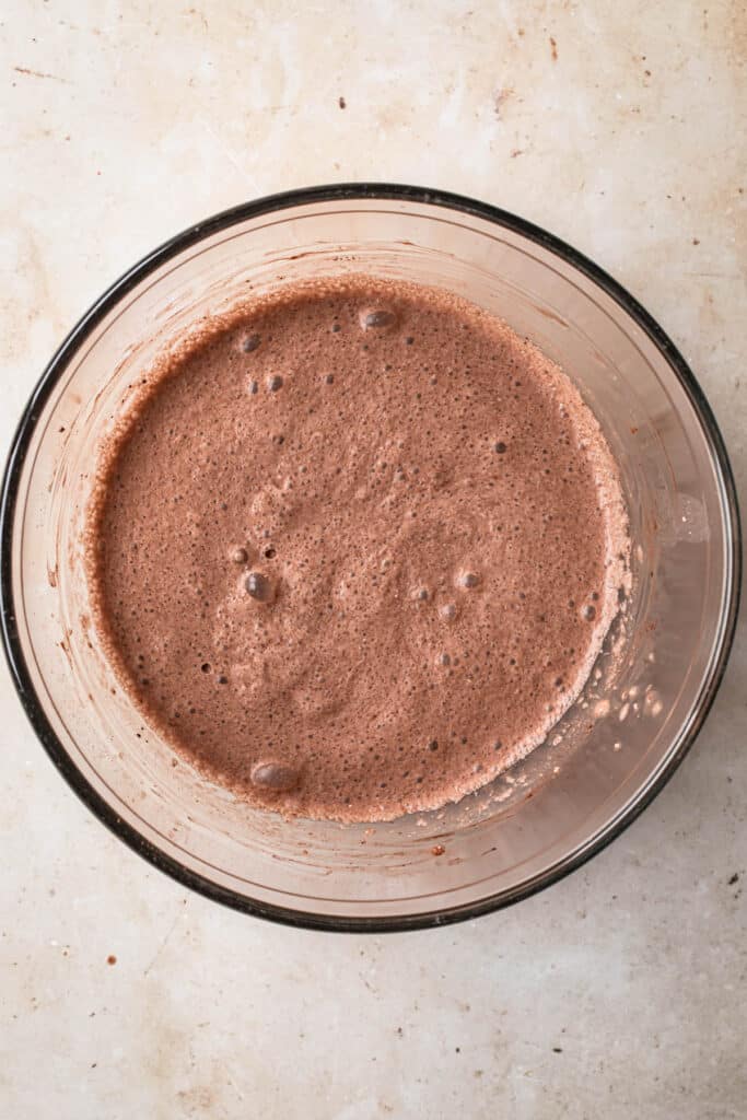All ingredients for chocolate chia pudding whisked together in a medium glass mixing bowl.