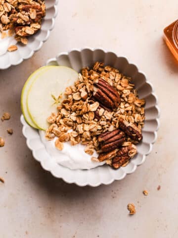 Healthy gingerbread granola with pecans in a bowl with thin apple slices and yoghurt.