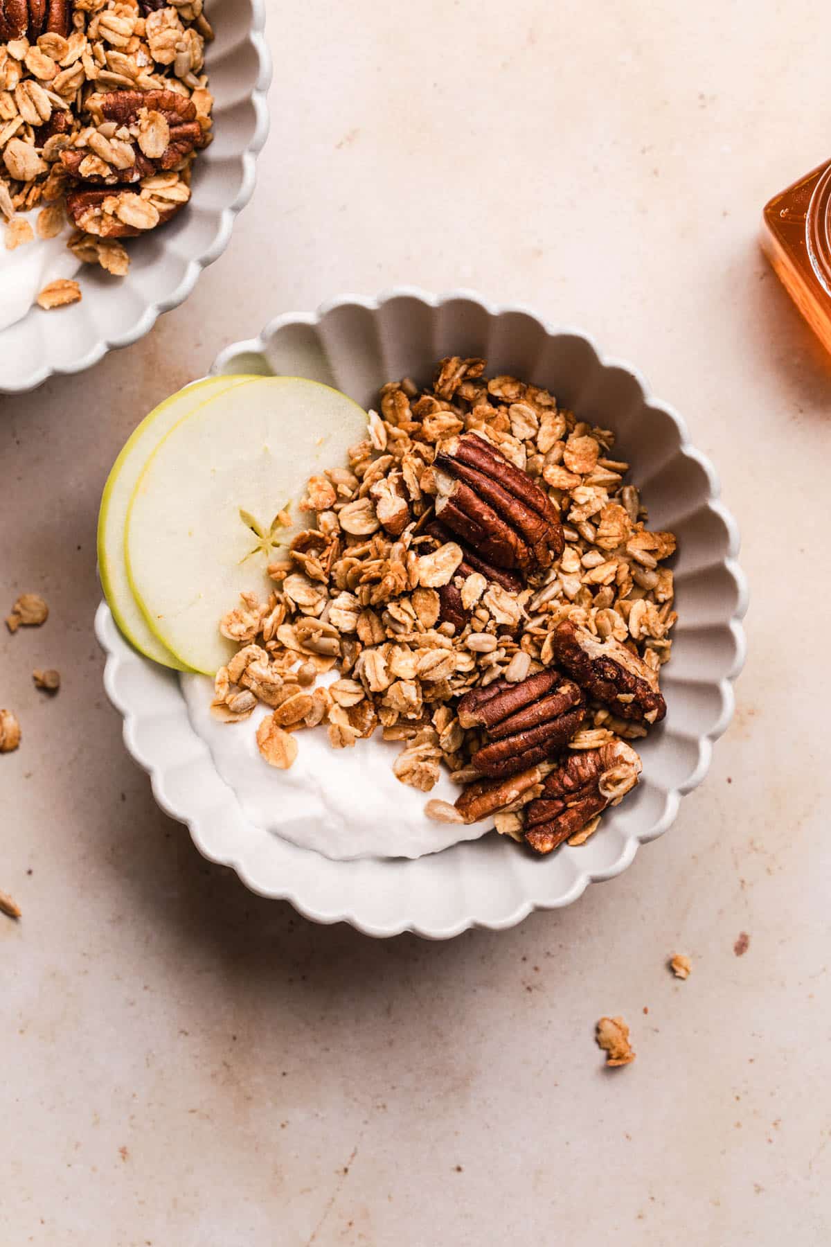 Healthy gingerbread granola with pecans in a bowl with thin apple slices and yoghurt.