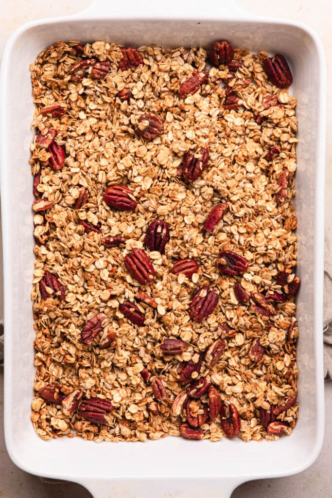 Gingerbread granola baked until golden in a large white baking dish.