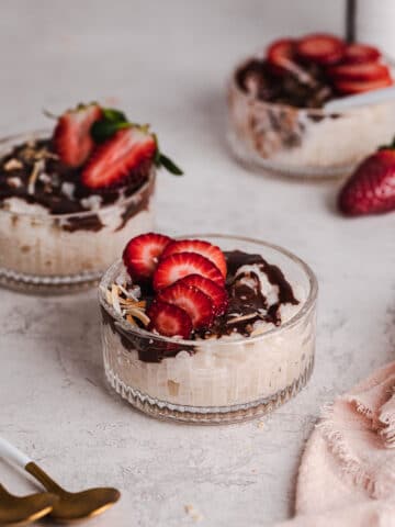 vanilla rice pudding in glass dish with dairy free chocolate sauce, topped with strawberries