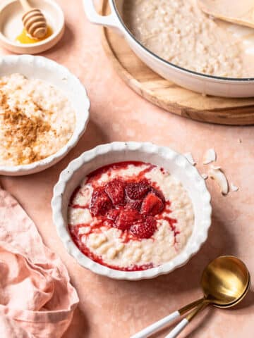 Dairy free rice pudding in a white bowl topped with stewed strawberries.