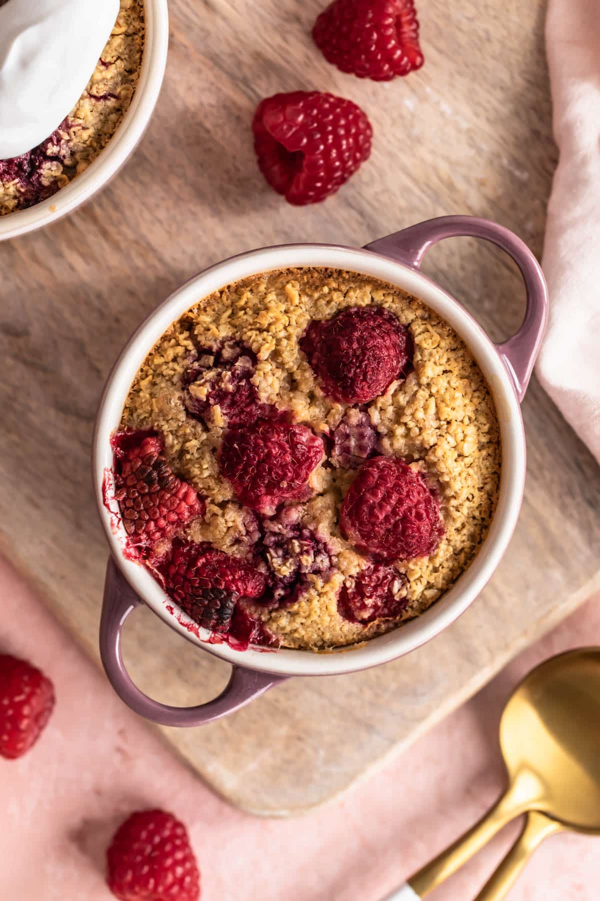 Raspberry Baked Oats in a small ramekin, with raspberries to the side.