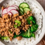 Ground chicken rice bowl with thinly sliced cucumber, radish and green onion.
