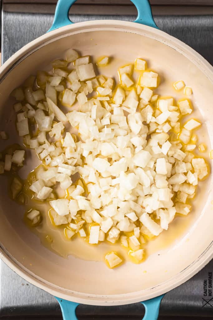 Diced onions sautéing in a fry pan with olive oil.