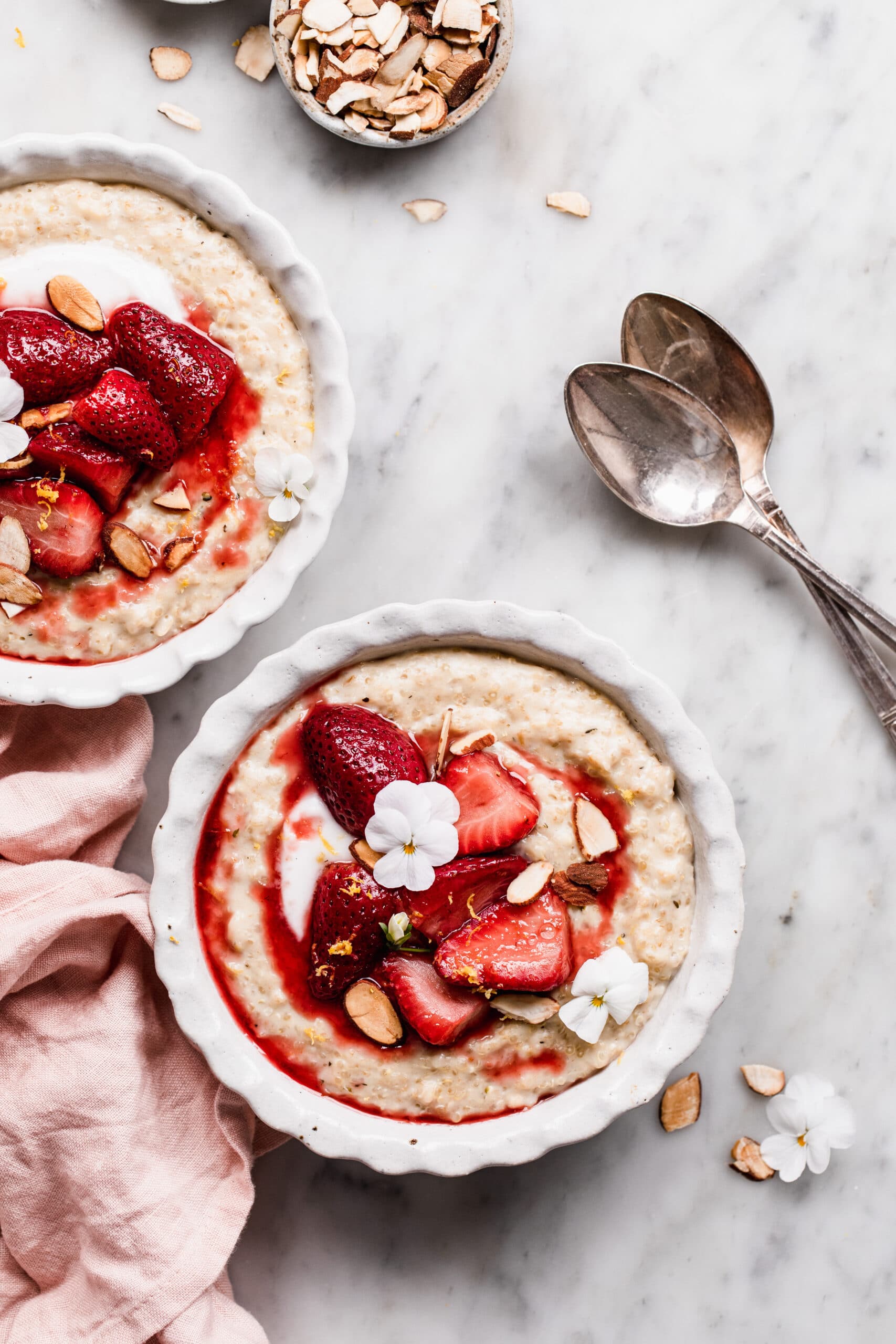 two bowls of quinoa oatmeal porridge topped with lightly stewed strawberries