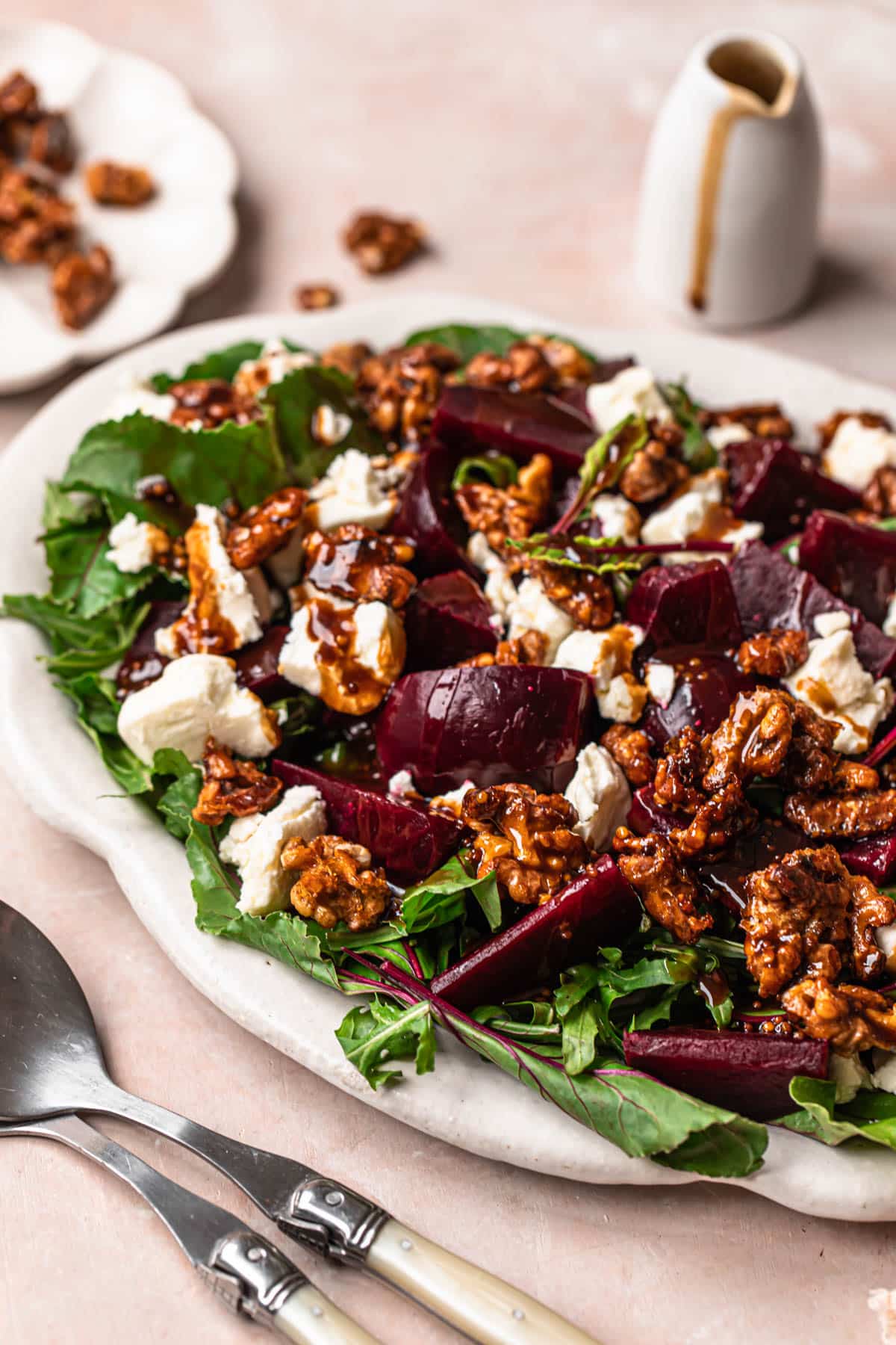 Beetroot salad with goat's cheese, honey candied walnuts and balsamic dressing, on a white serving platter.