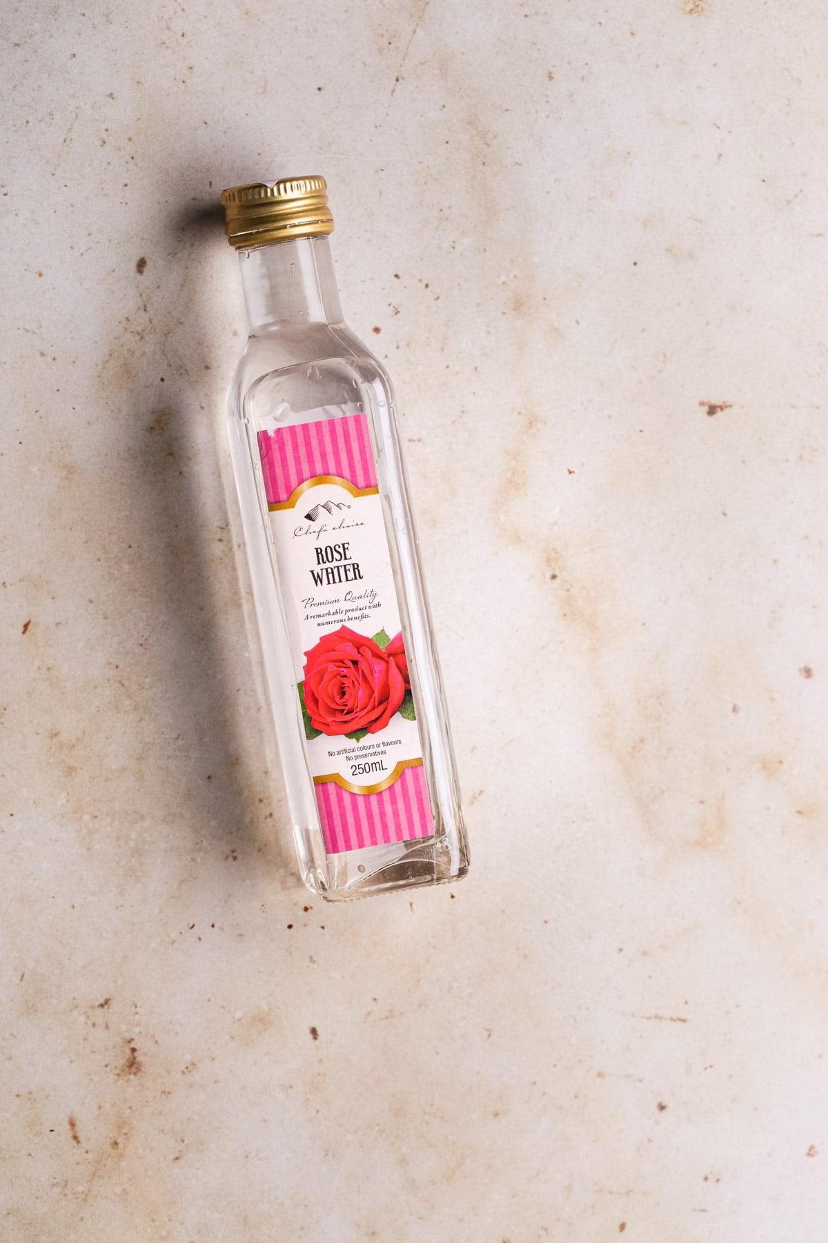 a bottle of rose water on caramel marble backdrop