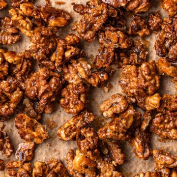 Close up of honey candied walnuts on a parchment paper lined baking tray.