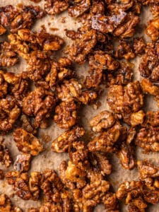 Close up of honey candied walnuts on a parchment paper lined baking tray.