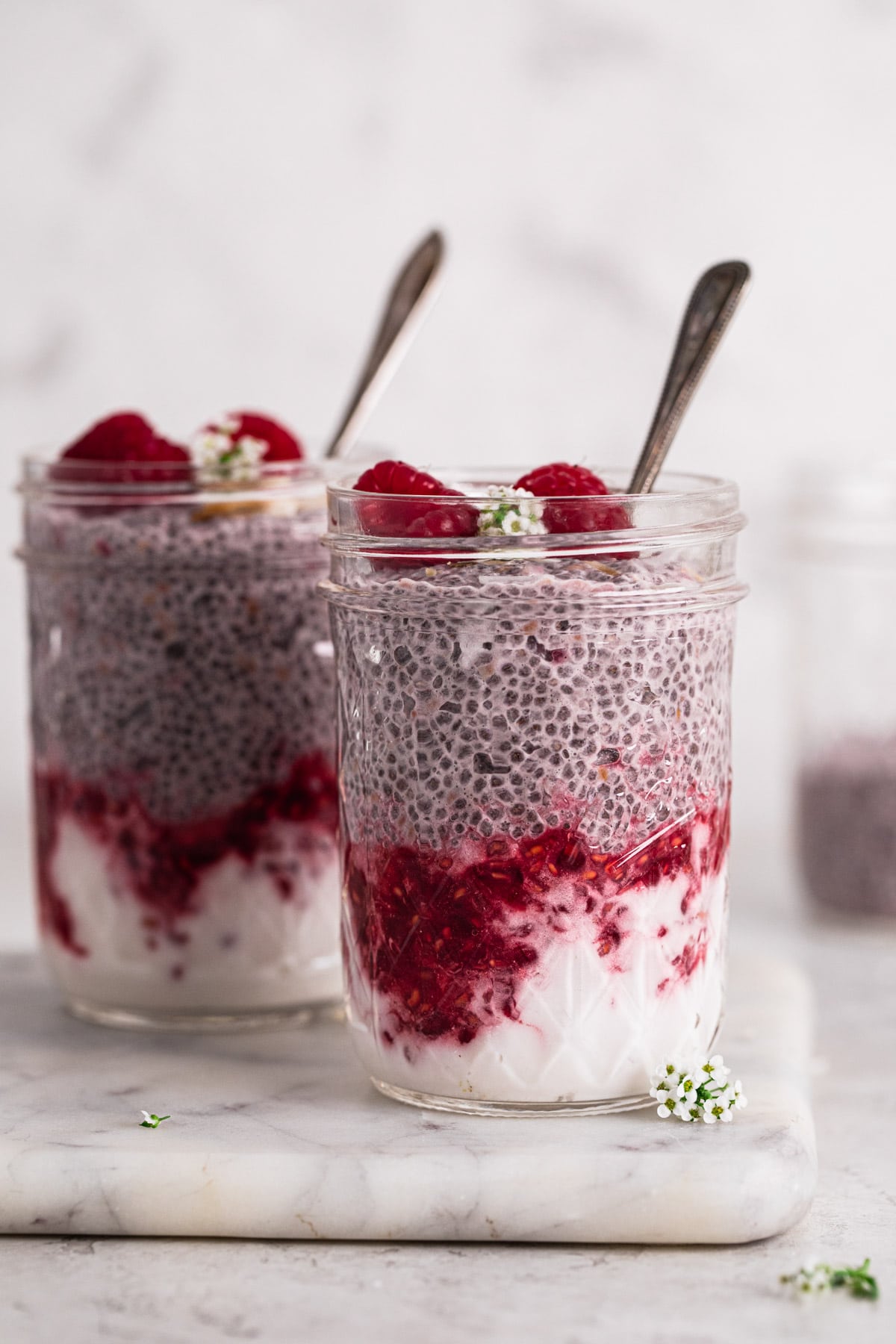 raspberry chia pudding in glass jars layered with yoghurt and mashed raspberries