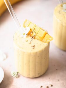 dairy free mango banana smoothie in glass with glass straw