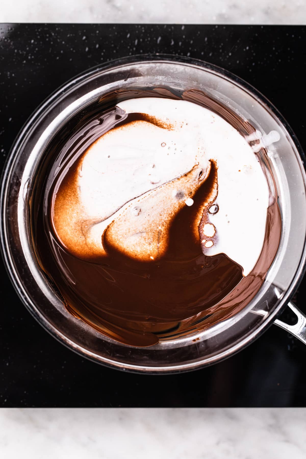 Dark chocolate and coconut milk mixing together to make vegan chocolate ganache.