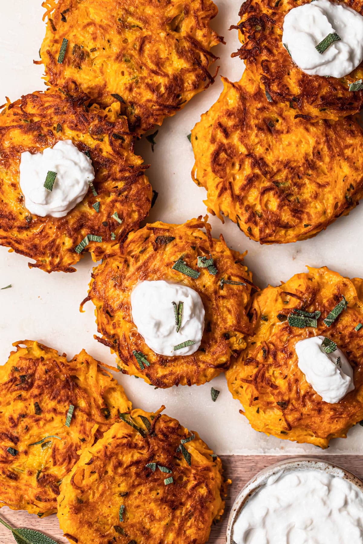 Butternut squash fritters on a marble serving board with garlic yoghurt dipping sauce.