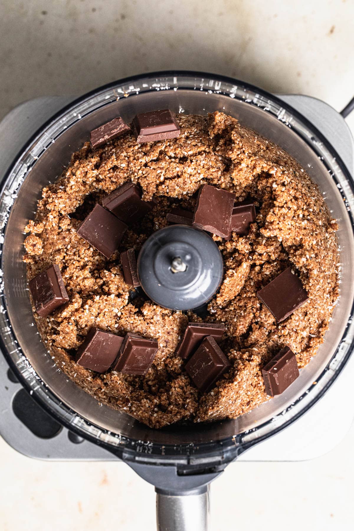 Chocolate added to peanut butter bliss balls mixture in food processor drum.