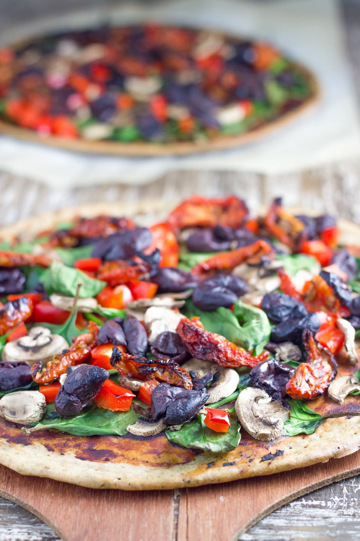 Buckwheat Pizza topped with olives, spinach and capsicum.