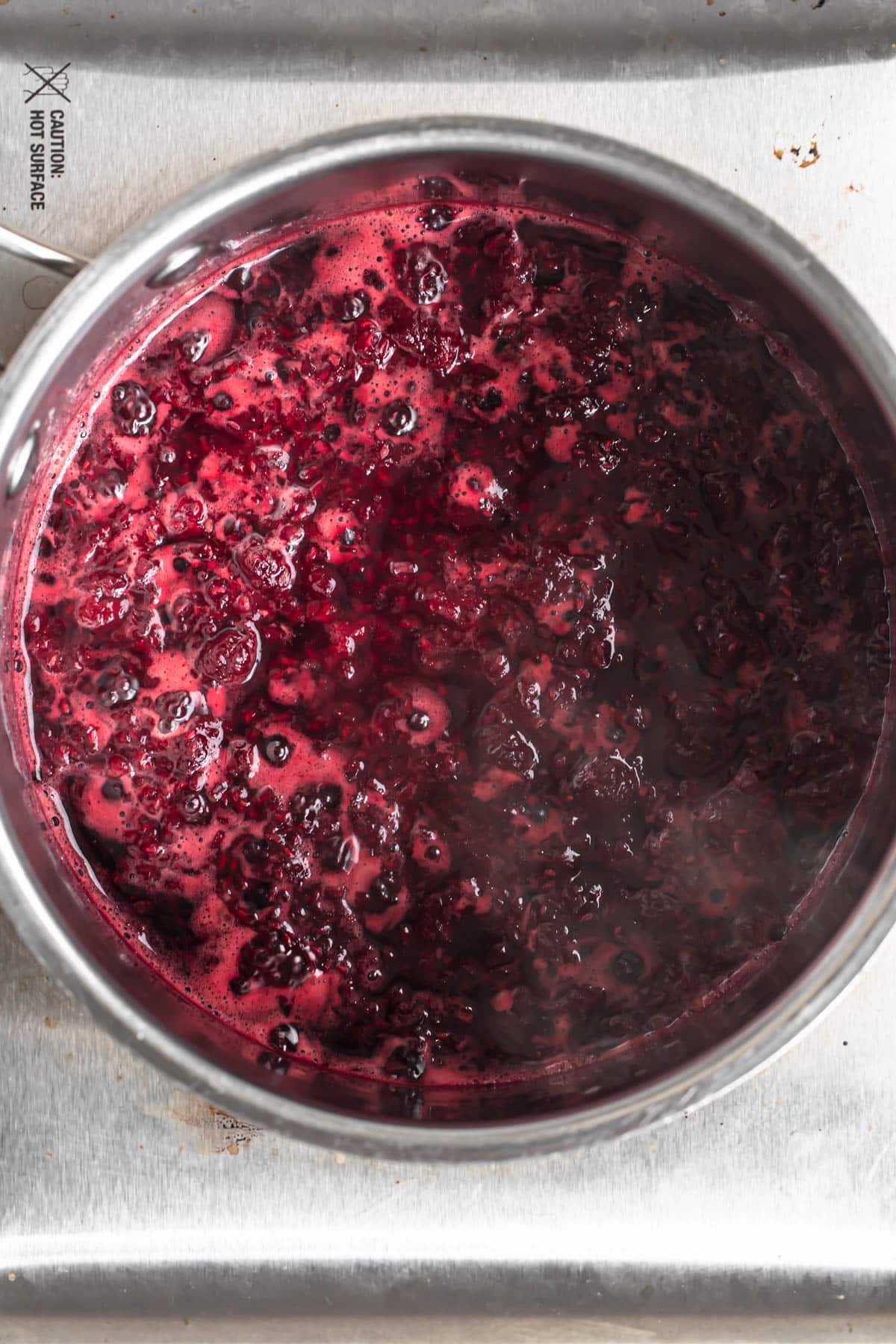 Raspberry compote simmering in a saucepan.