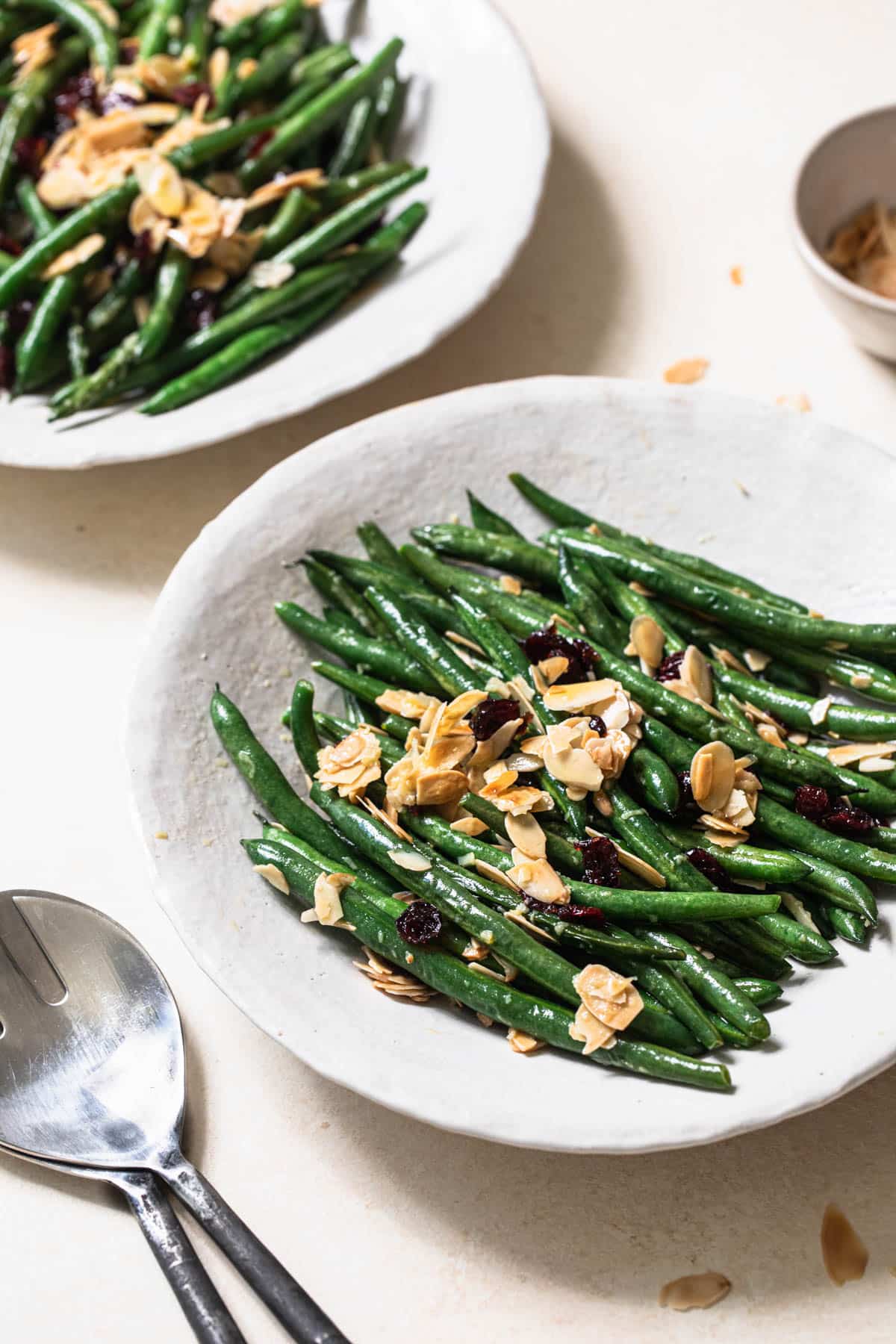 Green beans, cranberries and almonds served in white bowl.