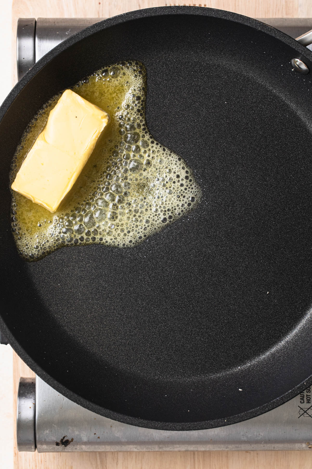 Butter melting in a black frypan.