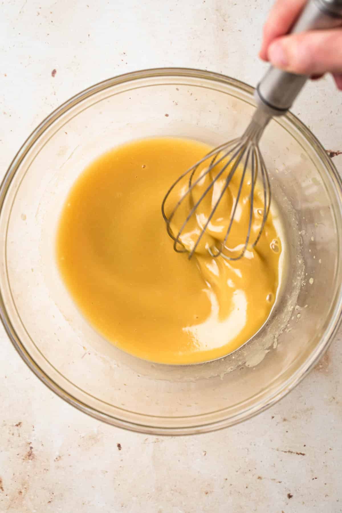 Maple dijon salad dressing whisked together in a medium glass mixing bowl.