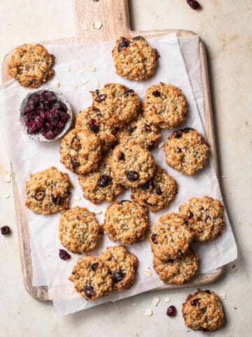 Healthy banana oat cookies on a board with dried cranberries in the background.