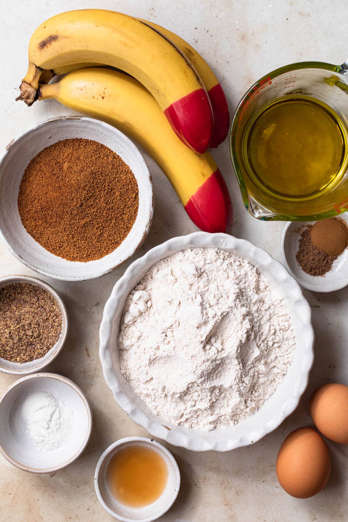 All ingredients needed to make gluten free banana muffins laid out in individual bowls.