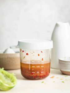 Chili lime dressing in a glass jar with an airtight silicon lid.