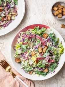 Dill pickle chopped salad in a white and pink bowl.