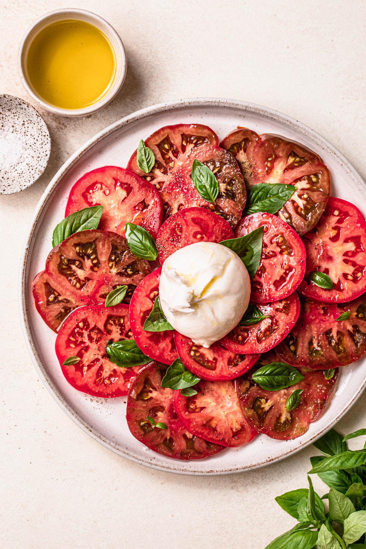 Burrata caprese salad made with heirloom tomatoes, served on a white ceramic plate.