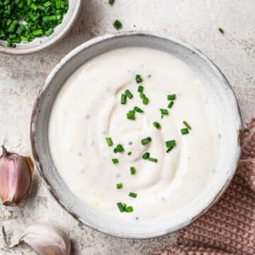 Close up photo of creamy garlic dressing topped with finely chopped fresh chives.