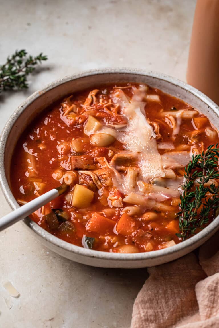 Shaved parmesan cheese on top of a bowl of minestrone soup.