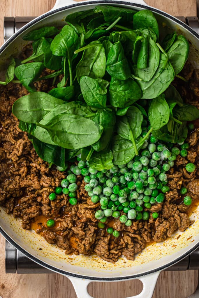 Frozen peas and baby spinach added to the Moroccan lamb mince.