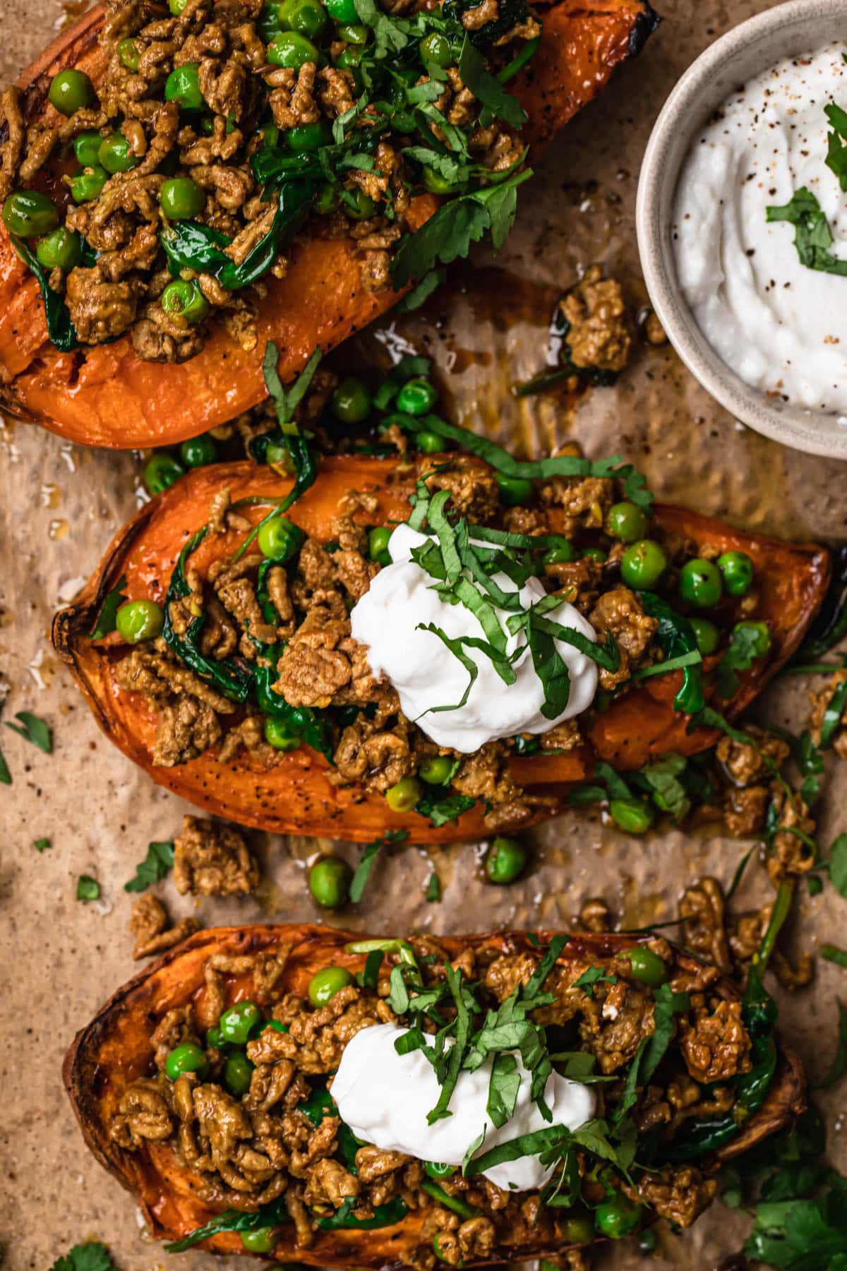 Close up photo of Moroccan Lamb Mince Stuffed sweet potatoes topped with garlic yoghurt and thinly sliced fresh cilantro.
