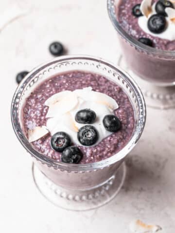 Blueberry chia pudding in a glass tumbler, topped with yogurt and blueberries.