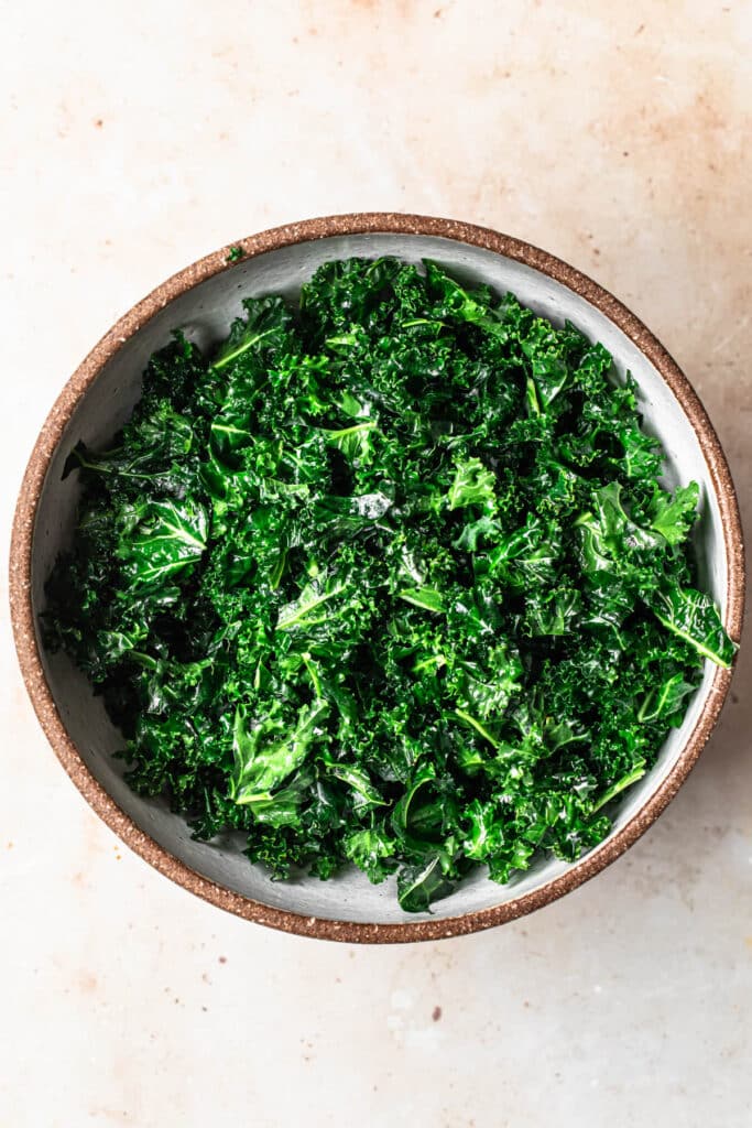 Roughly chopped curly kale in a large bowl, massaged with olive oil.